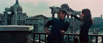 Movie still from “The Way of the Dragon” (1972), directed by Bruce Lee – A man standing on top of a balcony next to an old building; Medium shot, Low angle