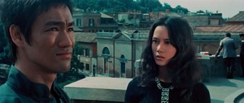 Movie still from “The Way of the Dragon” (1972), directed by Bruce Lee – A man and a woman standing next to each other on top of a building; Close Up shot, Low angle