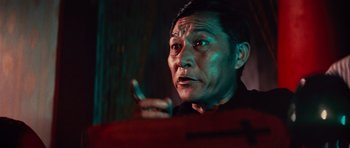 Movie still from “The Way of the Dragon” (1972), directed by Bruce Lee – An older asian man holding a cell phone in his hand; Close Up shot, Low angle