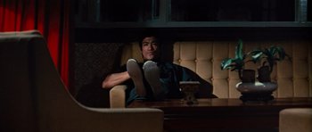Movie still from “The Way of the Dragon” (1972), directed by Bruce Lee – A man sitting on a couch with his feet up on a table; Medium shot, High angle