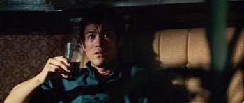 Movie still from “The Way of the Dragon” (1972), directed by Bruce Lee – A man sitting in the back seat of a car; Close Up shot, High angle
