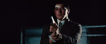 Movie still from “The Way of the Dragon” (1972), directed by Bruce Lee – A man in a suit and tie holding a pair of scissors; Close Up shot, Low angle