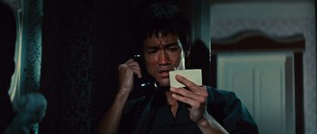 Movie still from “The Way of the Dragon” (1972), directed by Bruce Lee – A man on a cell phone holding a piece of paper; Close Up shot, Low angle
