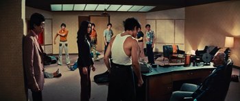 Movie still from “The Way of the Dragon” (1972), directed by Bruce Lee – A group of people standing in a room; Wide shot, High angle