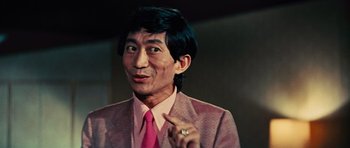 Movie still from “The Way of the Dragon” (1972), directed by Bruce Lee – A man wearing a pink suit and a pink tie; Close Up shot, Low angle