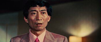 Movie still from “The Way of the Dragon” (1972), directed by Bruce Lee – A man in a pink suit and pink tie; Close Up shot, High angle