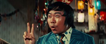Movie still from “The Way of the Dragon” (1972), directed by Bruce Lee – A man in a suit and tie is pointing to the side; Close Up shot, Low angle