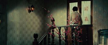 Movie still from “The Way of the Dragon” (1972), directed by Bruce Lee – A woman sitting on a stair rail looking out a window; Wide shot, High angle