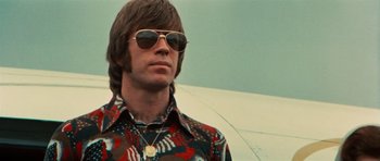 Movie still from “The Way of the Dragon” (1972), directed by Bruce Lee – A man wearing sunglasses and a colorful shirt; Close Up shot, Low angle