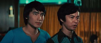 Movie still from “The Way of the Dragon” (1972), directed by Bruce Lee – Two asian men standing next to each other in front of a window; Close Up shot, Low angle