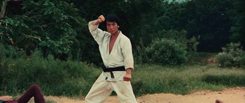 Movie still from “The Way of the Dragon” (1972), directed by Bruce Lee – A man in a karate outfit is doing a kick move; Medium shot, Low angle