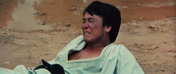 Movie still from “The Way of the Dragon” (1972), directed by Bruce Lee – A man in a white shirt is crying on the ground; Close Up shot, Low angle