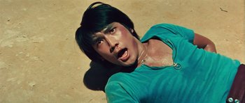 Movie still from “The Way of the Dragon” (1972), directed by Bruce Lee – A man laying on the ground in the dirt; Close Up shot, Overhead angle