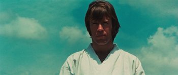 Movie still from “The Way of the Dragon” (1972), directed by Bruce Lee – A man in a white shirt is looking at the camera; Close Up shot, Low angle