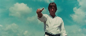 Movie still from “The Way of the Dragon” (1972), directed by Bruce Lee – A man in a karate uniform is pointing to the sky; Close Up shot, Low angle