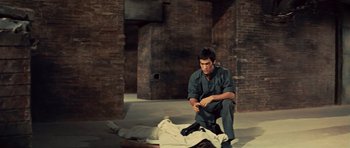 Movie still from “The Way of the Dragon” (1972), directed by Bruce Lee – A man kneeling down next to a dead body; Wide shot, High angle