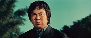 Movie still from “The Way of the Dragon” (1972), directed by Bruce Lee – A person wearing a suit and tie; Close Up shot, Low angle