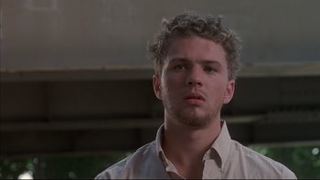 Movie still from “The Way of the Gun” (2000), directed by Christopher McQuarrie – A man with a beard and curly hair looking at the camera; Close Up shot, Low angle