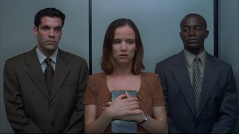 Movie still from “The Way of the Gun” (2000), directed by Christopher McQuarrie – A woman holding a book in front of two men in an elevator; Medium shot, Low angle