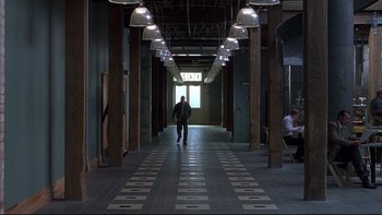 Movie still from “The Way of the Gun” (2000), directed by Christopher McQuarrie – A man walking down a hall way in a building; Extreme Wide shot, High angle