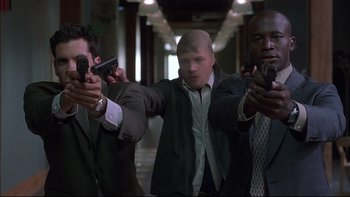 Movie still from “The Way of the Gun” (2000), directed by Christopher McQuarrie – A group of men holding guns in a hallway; Medium shot, Low angle