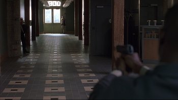 Movie still from “The Way of the Gun” (2000), directed by Christopher McQuarrie – A man taking a picture in a hallway; Wide shot, High angle