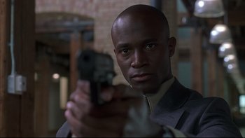 Movie still from “The Way of the Gun” (2000), directed by Christopher McQuarrie – A man in a suit holding a gun in his hand; Close Up shot, Low angle