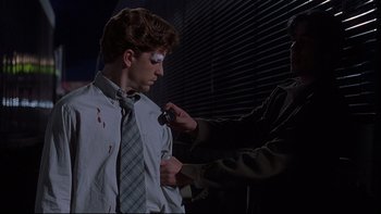 Movie still from “The Way of the Gun” (2000), directed by Christopher McQuarrie – A man is getting his face painted by another man; Medium shot, Over the shoulder angle