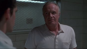 Movie still from “The Way of the Gun” (2000), directed by Christopher McQuarrie – An older man wearing a white shirt in front of a fence; Close Up shot, Low angle