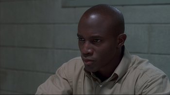 Movie still from “The Way of the Gun” (2000), directed by Christopher McQuarrie – A man sitting in front of a brick wall; Close Up shot, High angle