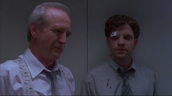 Movie still from “The Way of the Gun” (2000), directed by Christopher McQuarrie – Two men standing next to each other in front of a wall; Medium shot, Low angle