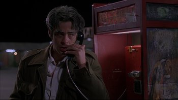 Movie still from “The Way of the Gun” (2000), directed by Christopher McQuarrie – A man holding a phone up to his ear while standing in front of a fire hydrant; Close Up shot, Low angle