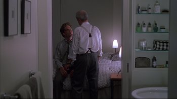 Movie still from “The Way of the Gun” (2000), directed by Christopher McQuarrie – Two men standing next to each other in front of a bed; Medium shot, Over the shoulder angle
