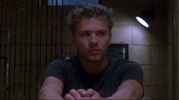 Movie still from “The Way of the Gun” (2000), directed by Christopher McQuarrie – A young man sitting in front of a window; Close Up shot, Low angle