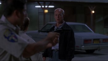 Movie still from “The Way of the Gun” (2000), directed by Christopher McQuarrie – An older man holding a gun in a parking lot; Medium shot, Over the shoulder angle