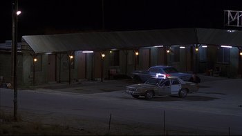 Movie still from “The Way of the Gun” (2000), directed by Christopher McQuarrie – A police car parked in front of a motel at night; Extreme Wide shot, High angle