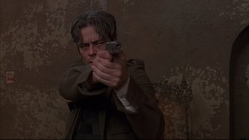 Movie still from “The Way of the Gun” (2000), directed by Christopher McQuarrie – A man holding a gun while wearing glasses; Close Up shot, Low angle