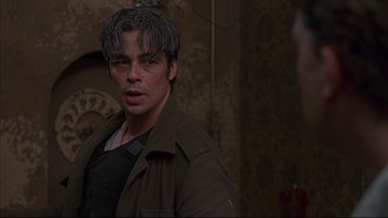 Movie still from “The Way of the Gun” (2000), directed by Christopher McQuarrie – A young man in a brown jacket is looking at the camera; Close Up shot, Over the shoulder angle