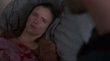 Movie still from “The Way of the Gun” (2000), directed by Christopher McQuarrie – A woman laying in a bed looking sad; Close Up shot, Overhead angle