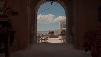 Movie still from “The Way of the Gun” (2000), directed by Christopher McQuarrie – An archway leading to an outdoor dining area; Extreme Wide shot, Low angle