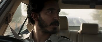 Movie still from “The Wedding Guest” (2018), directed by Michael Winterbottom – A person sitting in a car; Close Up shot, Over the shoulder angle