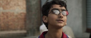 Movie still from “The Wedding Guest” (2018), directed by Michael Winterbottom – A young man wearing glasses looking up at the sky; Close Up shot, Low angle