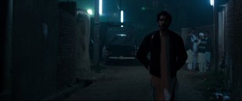 Movie still from “The Wedding Guest” (2018), directed by Michael Winterbottom – A man walking down a street at night; Medium shot, Low angle