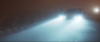 Movie still from “The Wedding Guest” (2018), directed by Michael Winterbottom – A car driving down a street with a light on; Extreme Wide shot, High angle
