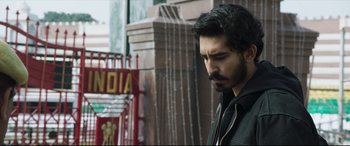 Movie still from “The Wedding Guest” (2018), directed by Michael Winterbottom – A man with a beard is standing outside; Close Up shot, Low angle