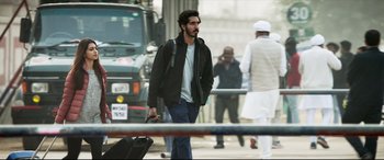 Movie still from “The Wedding Guest” (2018), directed by Michael Winterbottom – A man walking down a street holding a suitcase; Medium shot, Low angle