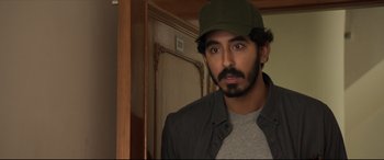 Movie still from “The Wedding Guest” (2018), directed by Michael Winterbottom – A person wearing a hat; Close Up shot, Over the shoulder angle