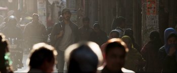 Movie still from “The Wedding Guest” (2018), directed by Michael Winterbottom – A group of people walking down a street; Medium shot, Over the shoulder angle