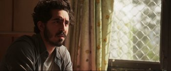 Movie still from “The Wedding Guest” (2018), directed by Michael Winterbottom – A person sitting in front of a window; Close Up shot, Over the shoulder angle