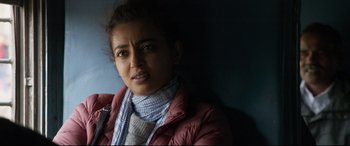 Movie still from “The Wedding Guest” (2018), directed by Michael Winterbottom – A woman wearing a jacket and a scarf is posing for a picture; Close Up shot, Over the shoulder angle
